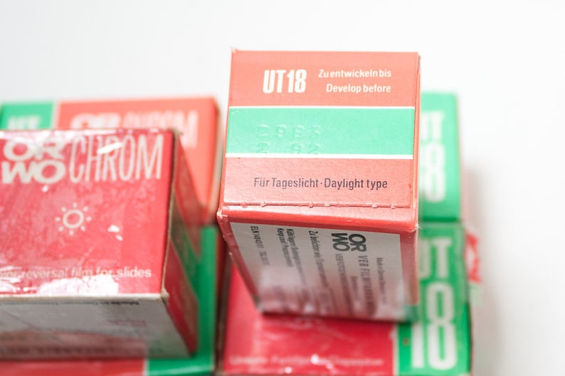 May include: A stack of red and green film boxes with the text "UT 18" and "ORWO CHROM" printed on them. The boxes are labeled "For Tageslicht - Daylight type" and "Zu entwickein bis - Develop before".