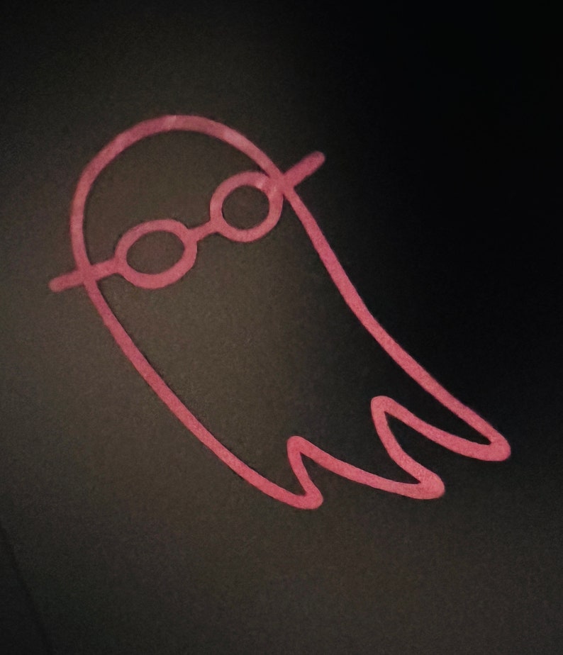 May include: A pink ghost with a pair of glasses drawn on a black background.