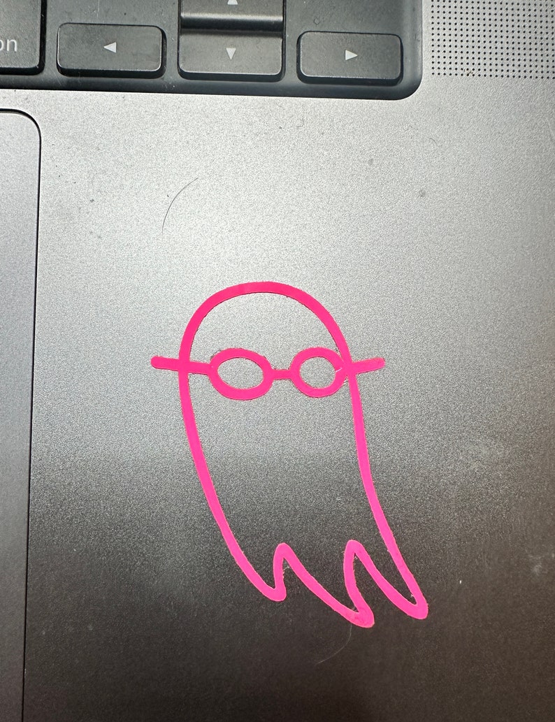 May include: A pink ghost with glasses drawn on a silver laptop.