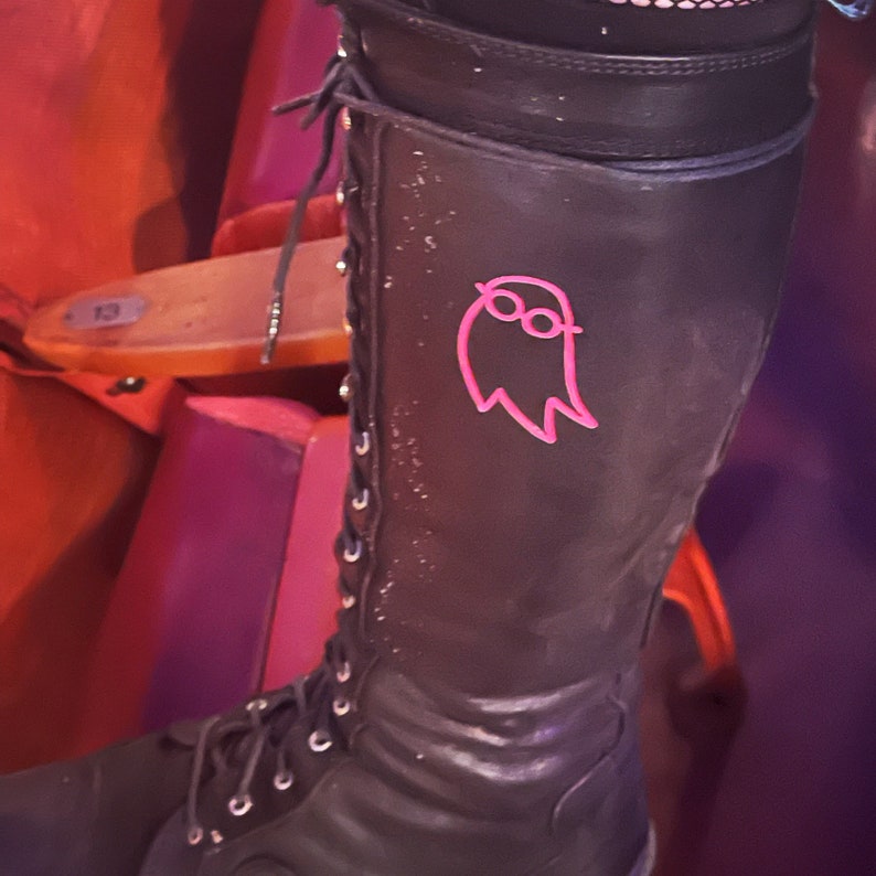May include: Black leather boots with a pink ghost design on the side. The ghost has a pair of glasses.