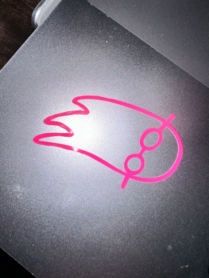 May include: A pink comet with a circle at the end, drawn on a gray surface.