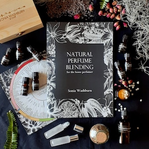 May include: A black and white book titled "Natural Perfume Blending for the home perfumer" by Sonia Washburn, surrounded by essential oils, a perfume wheel, and other natural ingredients.