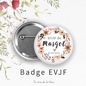 Op de afbeelding: Een witte button met een bloemenkransontwerp in perzik- en bruintinten. De button heeft de tekst "EVJF de Margot" en de datum "25.05.2024". De woorden "Badge EVJF" staan onderaan.
