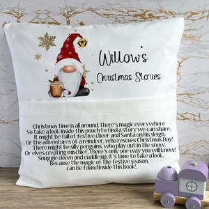 May include: White pillow with a pocket on the front. The pillow has a gnome illustration with a red hat and a cup of hot cocoa. The text "Willow's Christmas Stories" is printed on the pillow.
