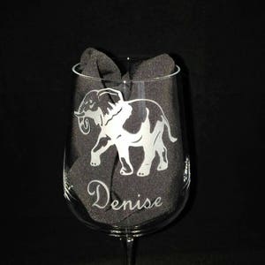 May include: A clear glass wine glass with an etched design of an elephant and the name "Denise".