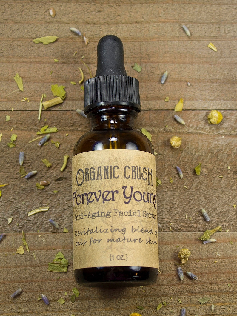 K&ouml;nnte beinhalten: Eine braune Glasflasche mit einer schwarzen Tropfflasche und einem Etikett mit der Aufschrift "ORGANIC CRUSH Forever Young Anti-Aging Facial Serum Revitalizing blend of oils for mature skin (1 OZ.)"