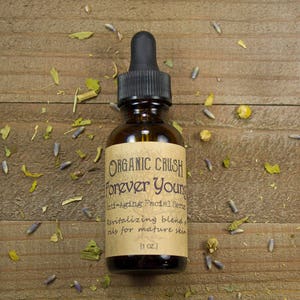 K&ouml;nnte beinhalten: Eine braune Glasflasche mit Tropfer und einem Etikett mit der Aufschrift "ORGANIC CRUSH Forever Young Anti-Aging Facial Serum Revitalizing blend oils for mature skin (1 oz.)"