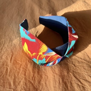 May include: A red, yellow, and blue floral headband with a navy blue elastic band.