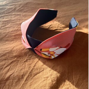 Peut inclure: Un bandeau rose et bleu marine avec un design noué et un imprimé abstrait coloré.