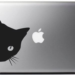 May include: A black cat silhouette sticker for a laptop, peeking from the left side of the screen. The cat has large eyes and a small nose. The sticker is placed on a silver laptop with the Apple logo visible.