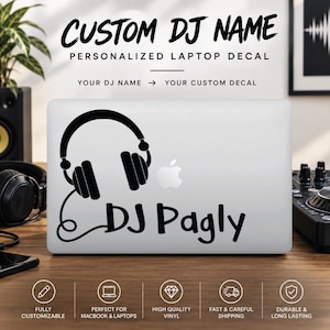 Op de afbeelding: Een zwarte vinyl laptopsticker aangebracht op een zilverkleurige laptopdeksel. Het ontwerp bevat een afbeelding van een koptelefoon met snoer en de tekst "DJ Pagly" in een gestileerd lettertype. Bovenaan staat "CUSTOM DJ NAME PERSONALIZED LAPTOP DECAL".