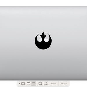 Peut inclure: Un ordinateur portable argenté avec un autocollant noir représentant le symbole de l'Alliance rebelle sur le couvercle.