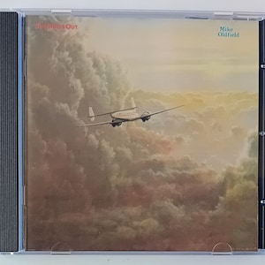 Könnte beinhalten: CD-Hülle mit dem Album "Five Miles Out" von Mike Oldfield. Das Cover zeigt ein Vintage-Flugzeug, das durch einen bewölkten Himmel fliegt. Der Albumtitel und der Name des Künstlers sind auf dem Cover aufgedruckt.