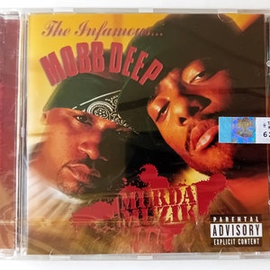 May include: A CD case with a red, yellow and black design. The front cover features a photo of two men, one with a black bandana and the other with a black hat. The text "The Infamous... MOBB DEEP" is printed in red and white. The album title "MURDA MUZIK" is printed in white on a red background. A parental advisory sticker is in the bottom right corner.