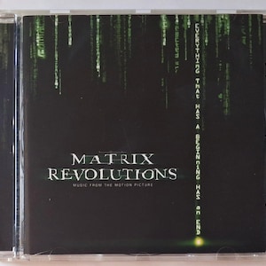 May include: A Matrix Revolutions music from the motion picture CD in a clear plastic jewel case. The cover features a black background with green digital rain code and the text: Everything that has a beginning has an end, Matrix Revolutions.