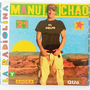 May include: A colorful album cover with a man wearing a black t-shirt with the words "El Golfo" printed on it. The album cover has the title "Manu Chao" and "La Radiolina" with the text "Y Ahora Que?" at the bottom.