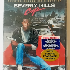 May include: A DVD case for the film Beverly Hills Cop. The cover features a red car with a man sitting on the bonnet holding a gun. The text "Beverly Hills Cop" is in white and red lettering. The case includes special features such as commentary by the director, cast and crew interviews, and the music from the film.