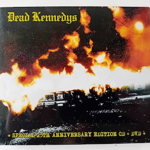 Può includere: Un set di CD e DVD dell'album "Frankenchrist" dei Dead Kennedys con una copertina nera e gialla che mostra un'auto in fiamme e il testo "SPECIAL 25TH ANNIVERSARY EDITION CD + DVD".