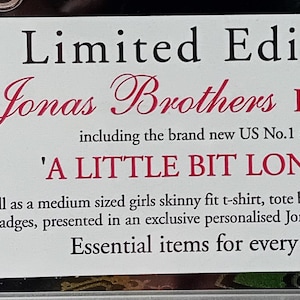 May include: White label with black text that reads "Limited Edition Jonas Brothers FAN PACK including the brand new US No. 1 album 'A LITTLE BIT LONGER' as well as a medium sized girls skinny fit t-shirt, tote bag, bracelet and set of 4 pin badges, presented in an exclusive personalised Jonas Brothers vanity case. Essential items for every fan!!!"  The label also has a barcode.