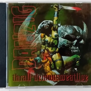 May include: A CD case with a green, red and black design. The front cover features a woman with a sword, a skull and the text "GIZZARD THRALL-DEMONSWORTHY LIVE".