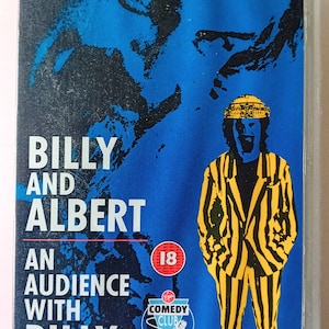 Pode incluir: Uma capa de fita VHS com um comediante em um terno listrado amarelo e preto. A capa é azul com um mapa do mundo no fundo. O texto na capa diz "Two Legendary Performances Billy and Albert An Audience with Billy Connolly" e "Comedy Club".