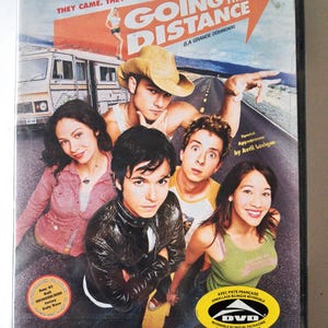 Può includere: Custodia DVD del film "Going the Distance" con un gruppo di giovani adulti su una strada. La copertina presenta il testo "They Came. They Saw. They Came." e "Going the Distance (La Grande Débandade)".