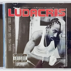 May include: A black and white album cover featuring a man with a shaved head and a goatee. The album title is "LUDACRIS" and the subtitle is "BACK FOR THE FIRST TIME". A parental advisory sticker is in the bottom left corner.