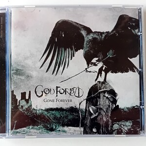 Op de afbeelding: CD-hoesje met het album "Gone Forever" van God Forbid. De cover toont een donkere kraai op een grafsteen, met een roos in zijn snavel. De bandnaam is in een gotisch lettertype. De achtergrond is een grijstinten landschap.