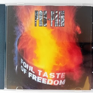 Op de afbeelding: Een CD-hoes met een zwarte achtergrond en een vurig oranje en rood ontwerp. De tekst "PRO-PAIN" staat in witte letters bovenaan de hoes. De tekst "FOUL TASTE OF FREEDOM" staat in witte letters onderaan de hoes.
