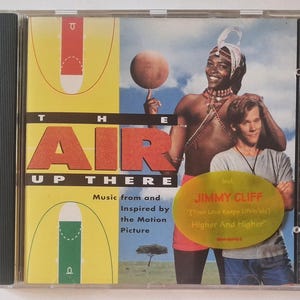 Op de afbeelding: Een cd-hoesje voor de soundtrack van de film The Air Up There. De hoes toont een basketballer die een bal op zijn vinger laat draaien, een persoon in een grijs t-shirt en een gele sticker met de vermelding van muziek door Jimmy Cliff.