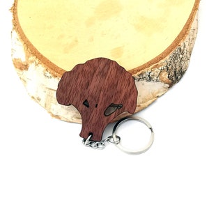 Puede incluir: Un llavero de madera con forma de coliflor. El llavero es de color marrón y tiene un anillo de metal plateado.