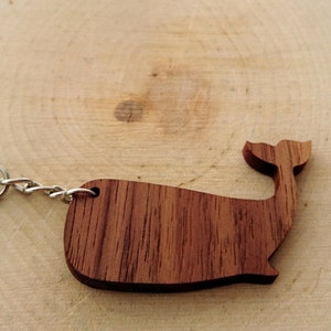 May include: A wooden whale keychain with a silver key ring and chain. The whale is made of dark brown wood with a natural grain pattern.