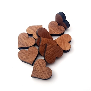 Peut inclure: Un tas de petits cœurs en bois, chacun avec une teinte brun foncé et un bord noir. Les cœurs sont disposés de manière aléatoire, certains se chevauchant.