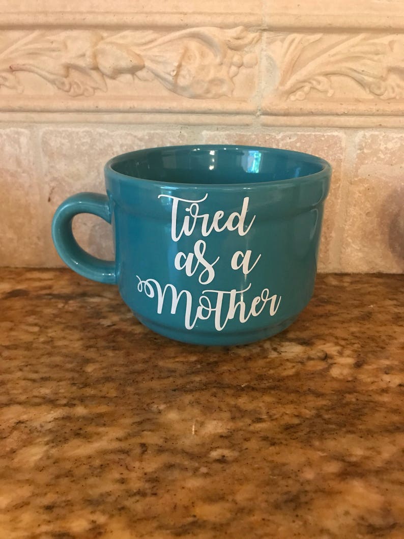 May include: Teal ceramic mug with white text that reads "Tired as a Mother".