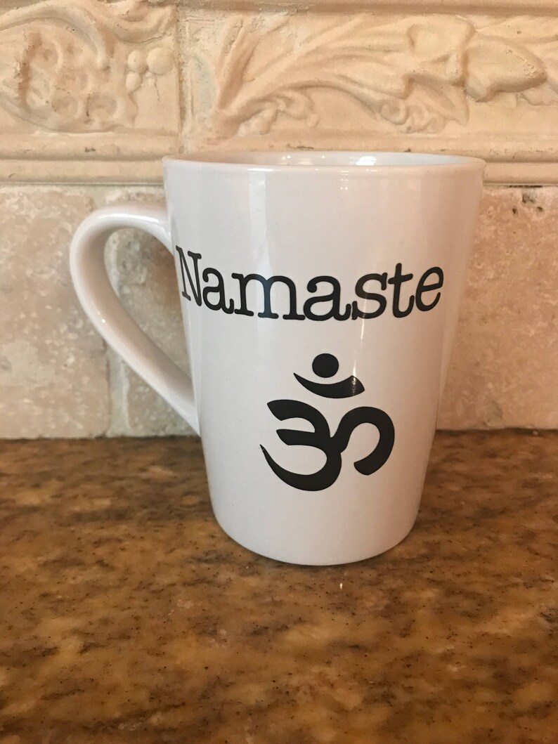 May include: White ceramic coffee mug with a black "Namaste" inscription and an Om symbol.