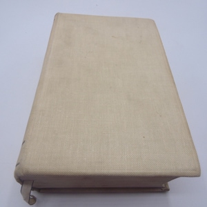 Puede incluir: Un libro de tapa dura de color crema con una cubierta de tela texturizada.