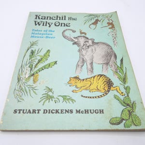 May include: A vintage children's book titled "Kanchil the Wily One: Tales of the Malayan Mouse-Deer" by Stuart Dickens McHugh. The cover features a colourful illustration of a mouse-deer, an elephant, and a tiger in a jungle setting.
