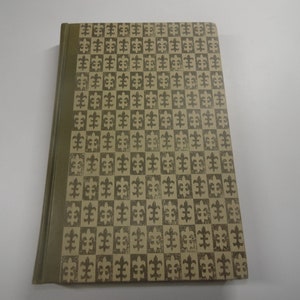 Pode incluir: Um livro castanho com uma capa estampada que apresenta um desenho repetitivo de símbolos de flor-de-lis em um padrão xadrez.