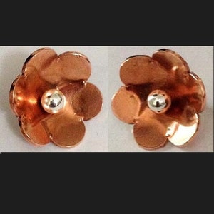 May include: A pair of copper flower-shaped earrings with a silver bead in the center of each flower.