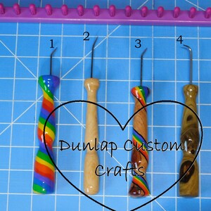 Peut inclure: Cinq crochets de m&eacute;tier &agrave; tisser en m&eacute;tal avec des manches d&eacute;coratifs, dont trois avec des motifs arc-en-ciel et deux avec des finitions en bois naturel. Les crochets sont num&eacute;rot&eacute;s de un &agrave; quatre, avec le texte Dunlap Custom Crafts en forme de c&oelig;ur.