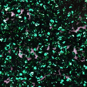 May include: A close-up of a green glitter background. The glitter is made up of small, iridescent pieces that reflect light.