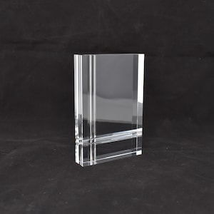 Könnte beinhalten: Ein klarer Glasbilderrahmen mit rechteckiger Form und abgeschrägten Kanten. Der Rahmen hat einen erhöhten Rand um die Öffnung.