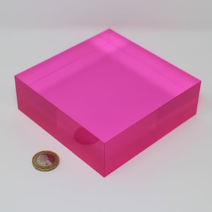 Könnte beinhalten: Ein leuchtend pinkfarbener, rechteckiger Acrylblock. Eine Münze liegt neben dem Block zum Größenvergleich. Der Block hat eine einfarbige, glatte, polierte Oberfläche. Die Kanten sind scharf und klar definiert.
