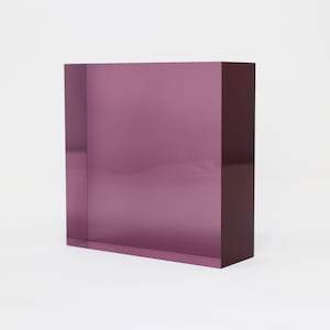 Könnte beinhalten: Ein quadratischer, durchsichtiger, lilafarbener Acrylblock.