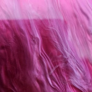 May include: Abstract image with a blend of pink and white hues, creating a flowing, marbled effect. The colors transition from light pink at the top to a deep magenta at the bottom, with swirling patterns.