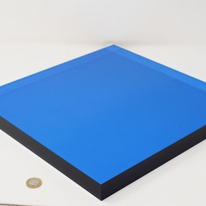 Könnte beinhalten: Ein quadratisches Stück blaues Acryl mit schwarzen Kanten. Das Acryl ist durchscheinend und hat einen leichten Glanz.