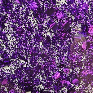 May include: Purple glitter with a variety of sizes and shapes. The glitter is scattered on a white background.