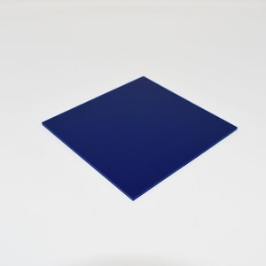 May include: A square, solid navy blue object is centrally positioned against a white backdrop. The object appears to be made of a smooth, flat material. The edges are sharp and well-defined, creating a clean, minimalist aesthetic.