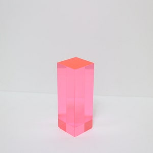 Könnte beinhalten: Ein leuchtend rosa Acrylblock, perfekt zum Präsentieren kleiner Gegenstände oder als dekoratives Element.