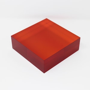 Könnte beinhalten: Ein quadratischer, durchsichtiger, roter Acrylblock.